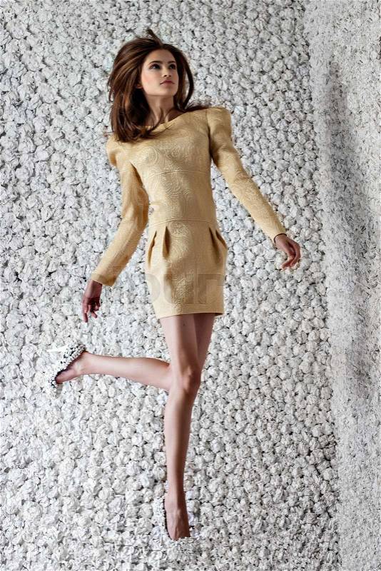Fashion model poses jumping in design elegant dress on white paper studio background. Fashion look.Stylish image.Skinny, stock photo