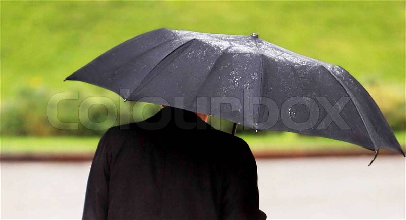 Businessman with umbrella walking in the rain, stock photo