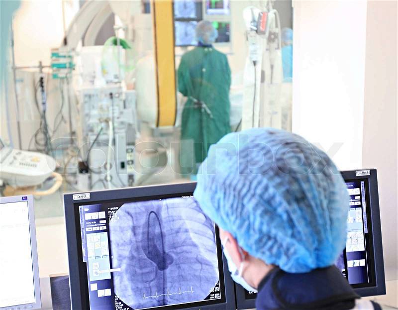 Doctor looking at the computer monitor during heart operation, stock photo