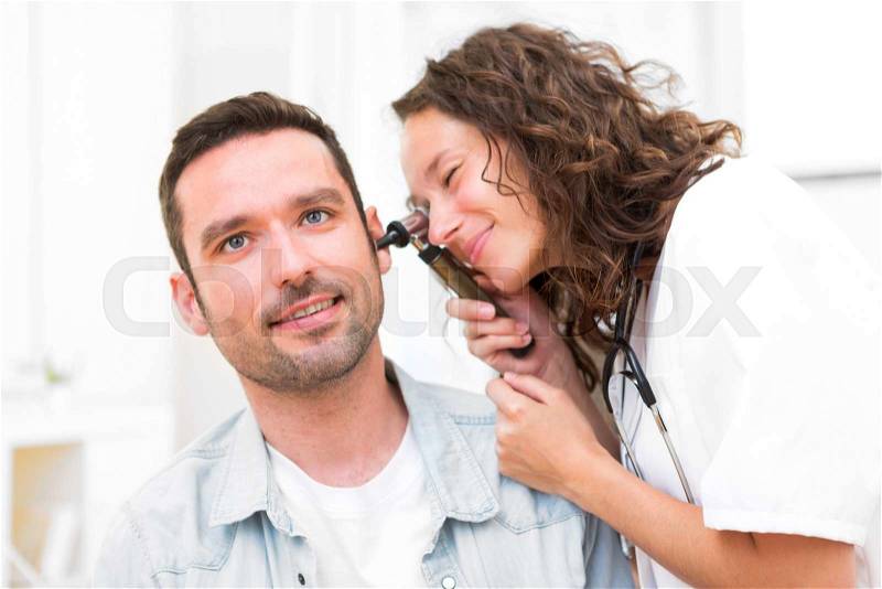 View of a Young attractive doctor checking patient\'s ear, stock photo