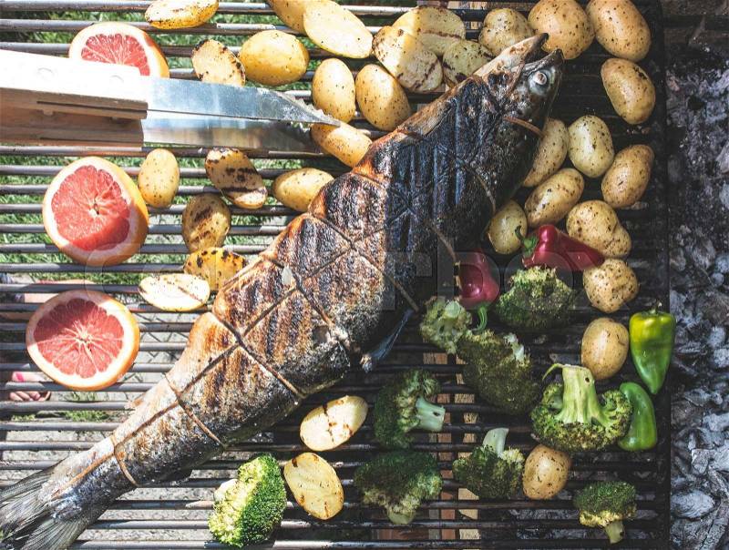 Roasting salmon fish on grill. Vegetables on grill in a garden, stock photo