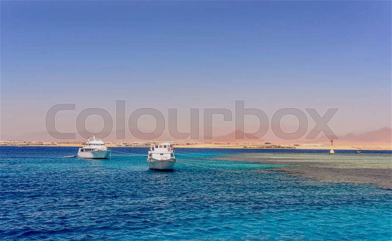 Group of tour ships and dive boats moored off an offshore reef and sand bar in a calm blue tropical ocean on a hot summer day, stock photo