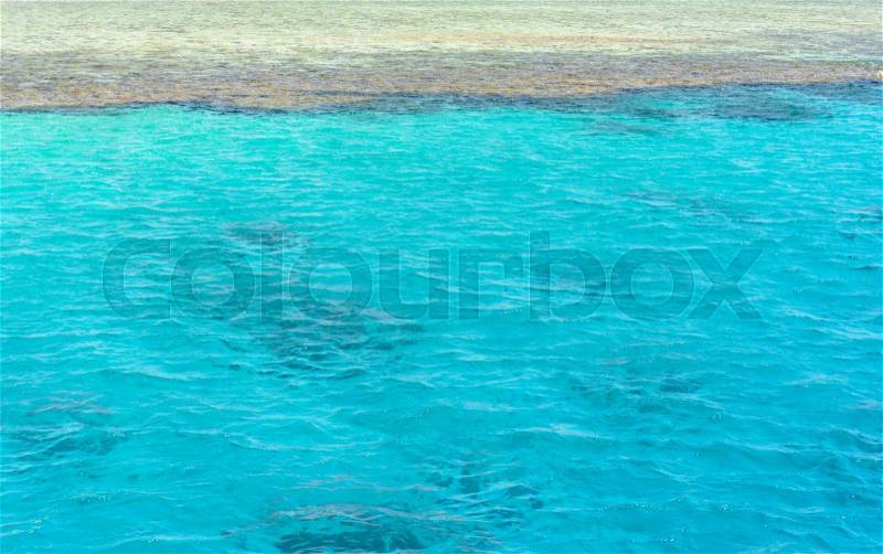 Crystal clear turquoise blue sea water lapping gently against a sandy shore or sand bank, conceptual of an idyllic summer vacation in the tropics, stock photo
