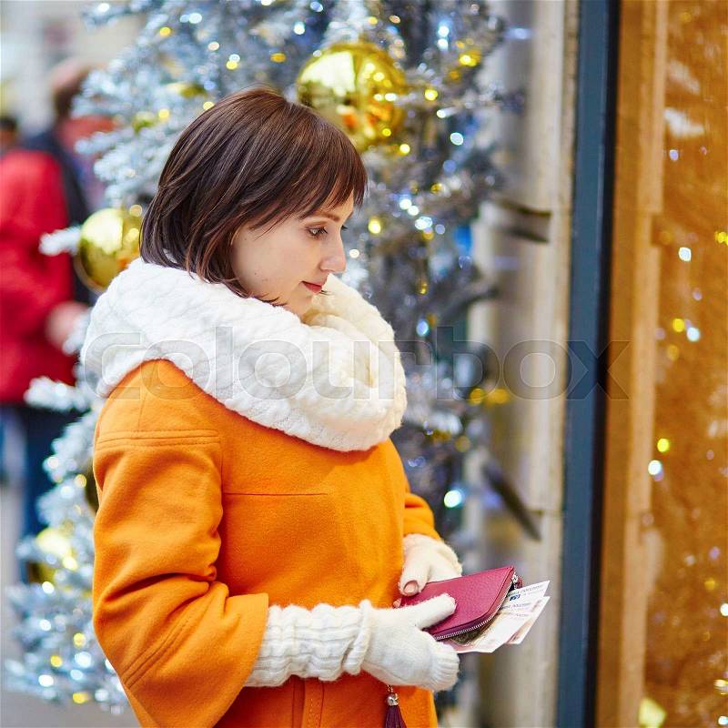 Worried young woman holding purse with Russian roubles in shopping mall decorated for Christmas, financial crisis in Russia concept, stock photo
