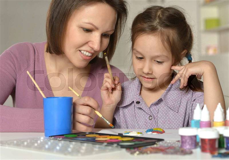 Little girl painting with her nice mother, stock photo