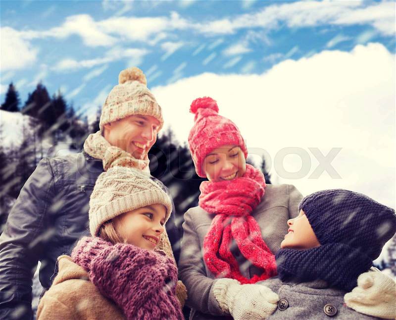 Family, childhood, season and people concept - happy family in winter clothes over snowy mountains background, stock photo
