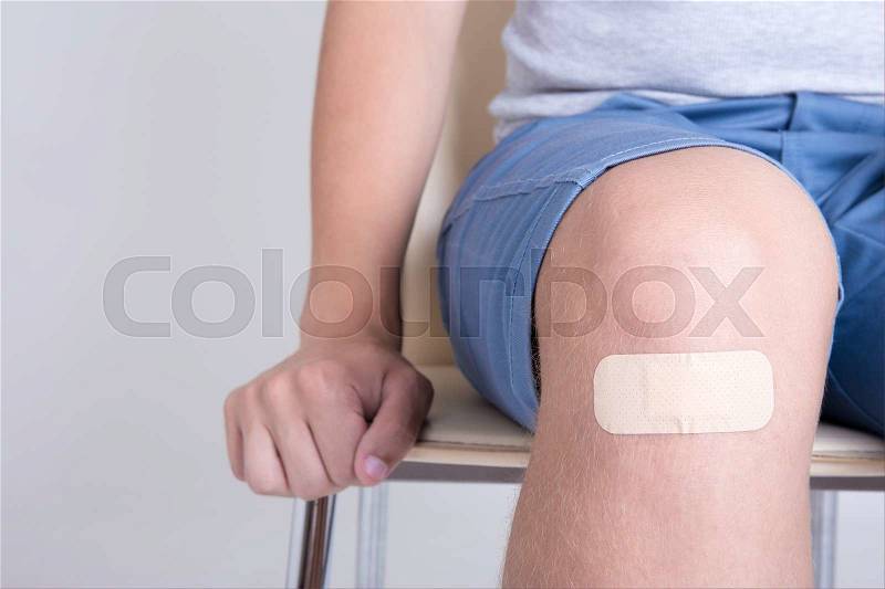 Close up of brown adhesive plaster on male knee, stock photo