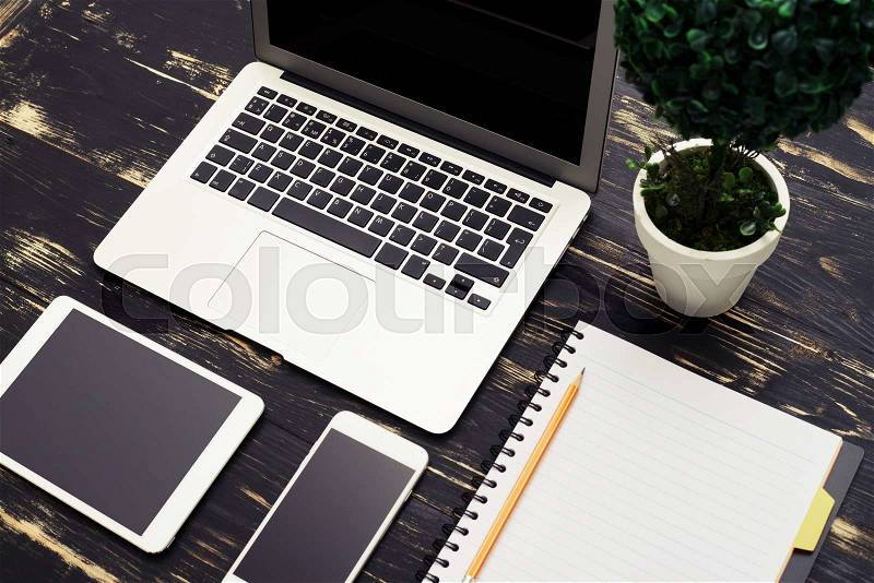 Top view of workspace with laptop, smartphone, tablet pc and empty notebook, stock photo