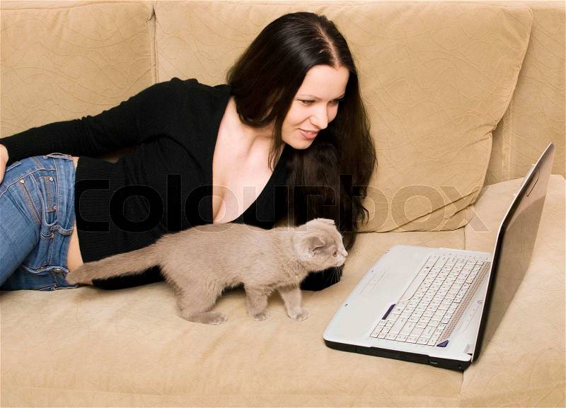 Woman and cat with laptop on a sofa, stock photo