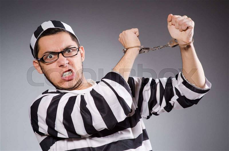 Young prisoner in handcuffs against gray, stock photo