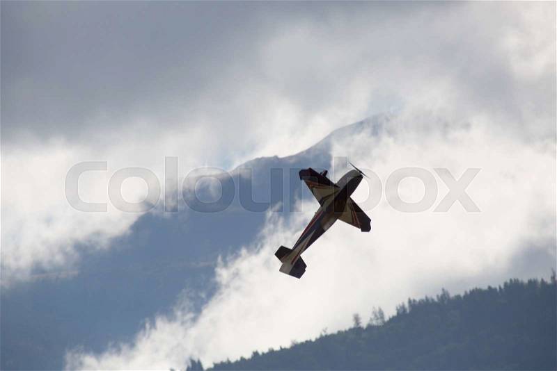 Plane make acrobatic flight between dark cloud, stock photo