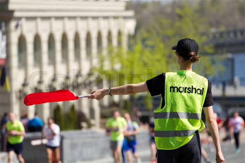 Volunteer holds a flag in his hand and points the way athletes runners, stock photo
