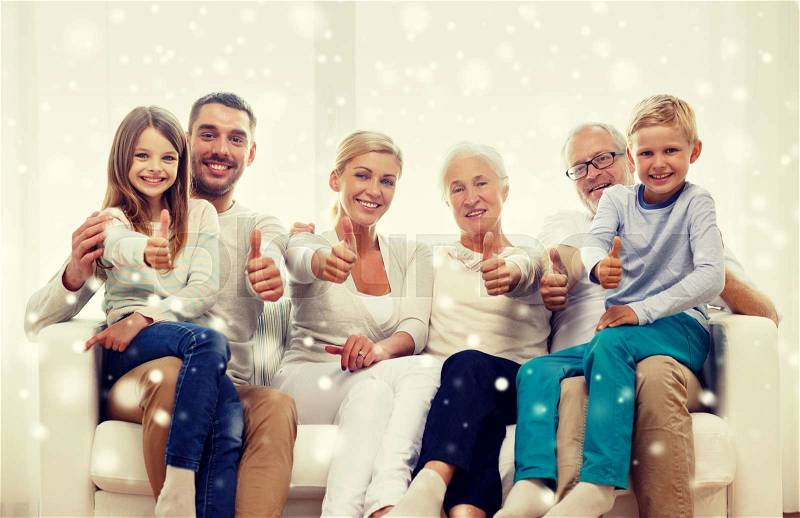 Family, happiness, generation and people concept - happy family sitting on couch and showing thumbs up gesture at home, stock photo