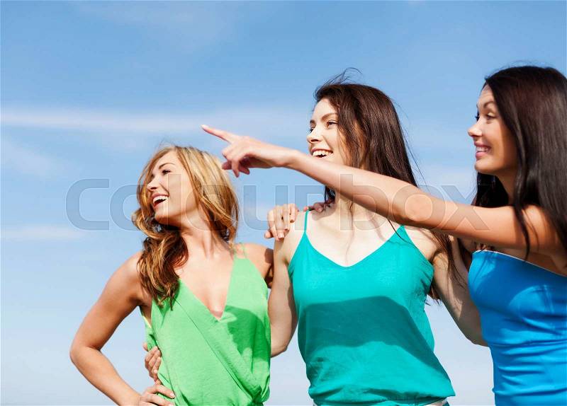 Summer holidays and vacation - girls walking on the beach and showing direction, stock photo