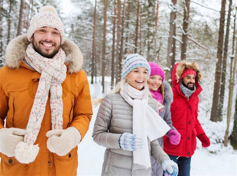 Love, relationship, season, friendship and people concept - group of smiling men and women running in winter forest, stock photo