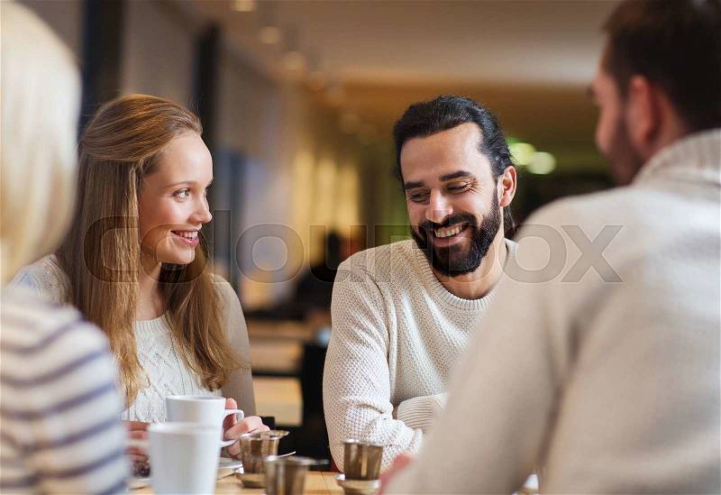 People, leisure, communication, eating and drinking concept - happy friends meeting and drinking tea or coffee at cafe, stock photo