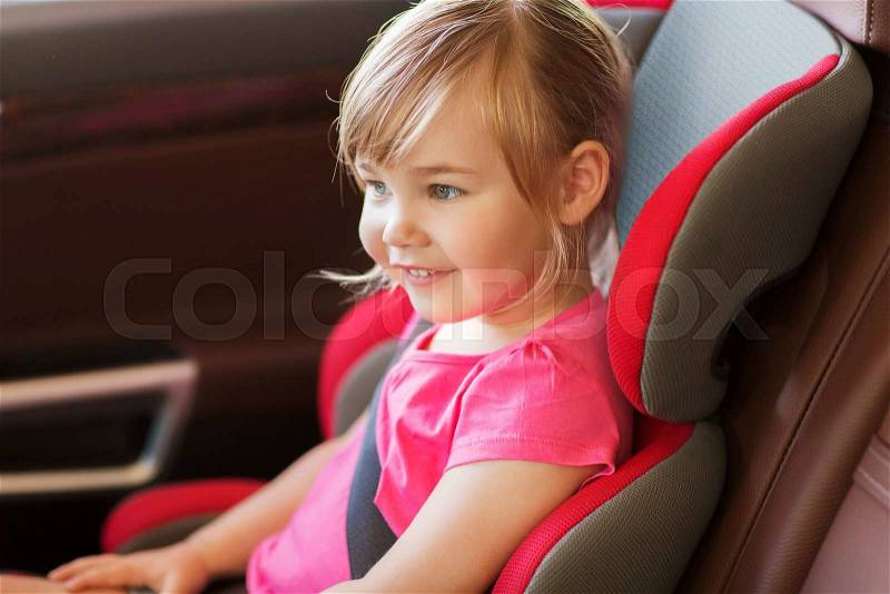 Transport, safety, childhood road trip and people concept - happy little girl sitting in baby car seat, stock photo