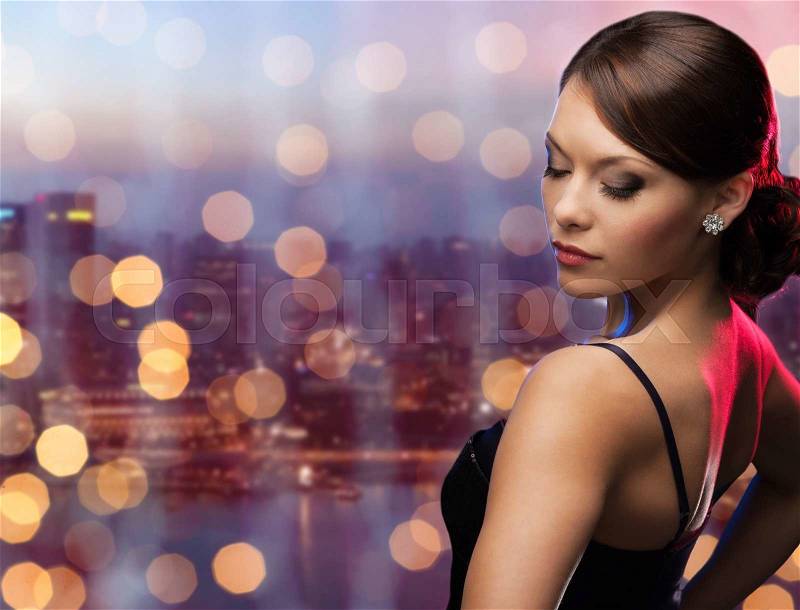 People, holidays, jewelry and luxury concept - woman face with diamond earring over night singapore city and lights background, stock photo
