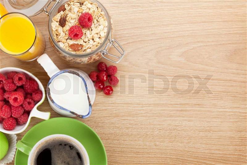 Healty breakfast with muesli, berries, orange juice, coffee and croissant. View from above on wooden table with copy space, stock photo