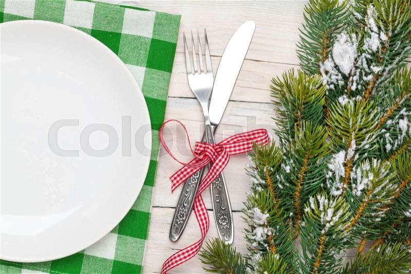 Empty plate, silverware and christmas tree. View from above over white wooden table background, stock photo