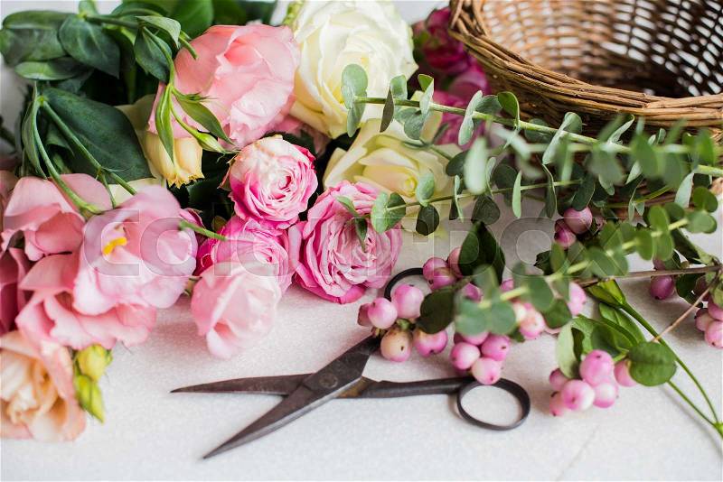 Fresh flowers, leaves, and tools to create a bouquet on a table, florist\'s workplace, stock photo