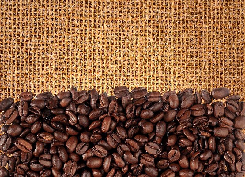 Coffee beans scattered on burlap can be used as background, stock photo