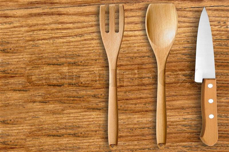 Wooden spoon, fork and knife on cutting board isolated on white background, stock photo