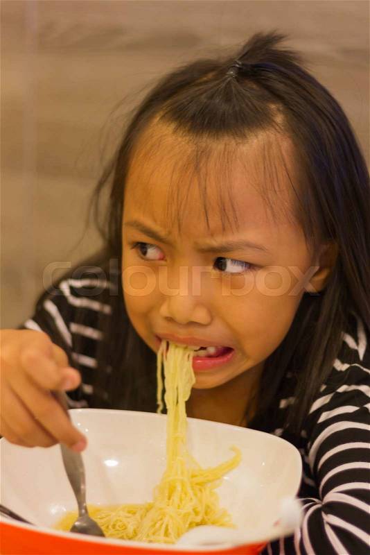 Portrait of bored noodles taste little asian kid, stock photo