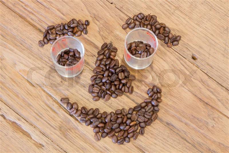 Coffee beans in smile face shape on wood table, stock photo
