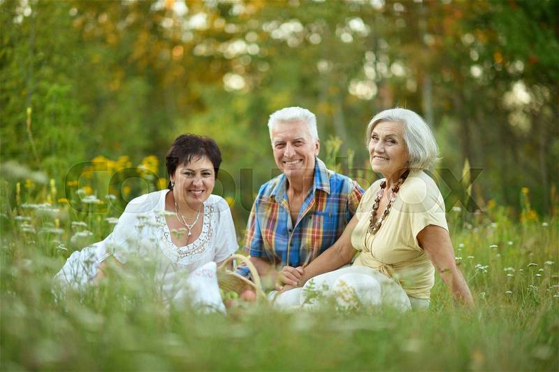 Happy elder people resting on grass at nature, stock photo