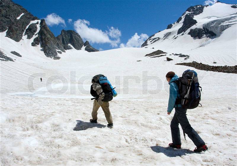 Couple of hikers climb to pass in high mountains, stock photo