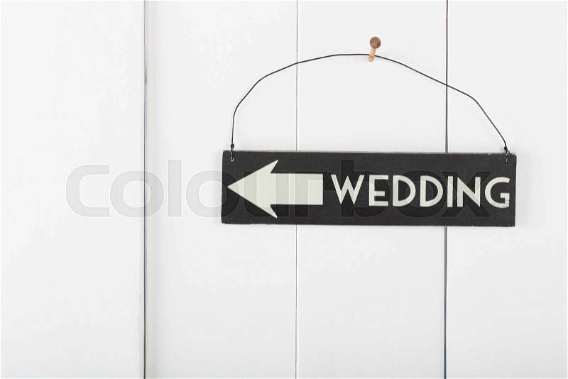 Wedding sign hanging on a wooden wall pointing the direction wedding, stock photo