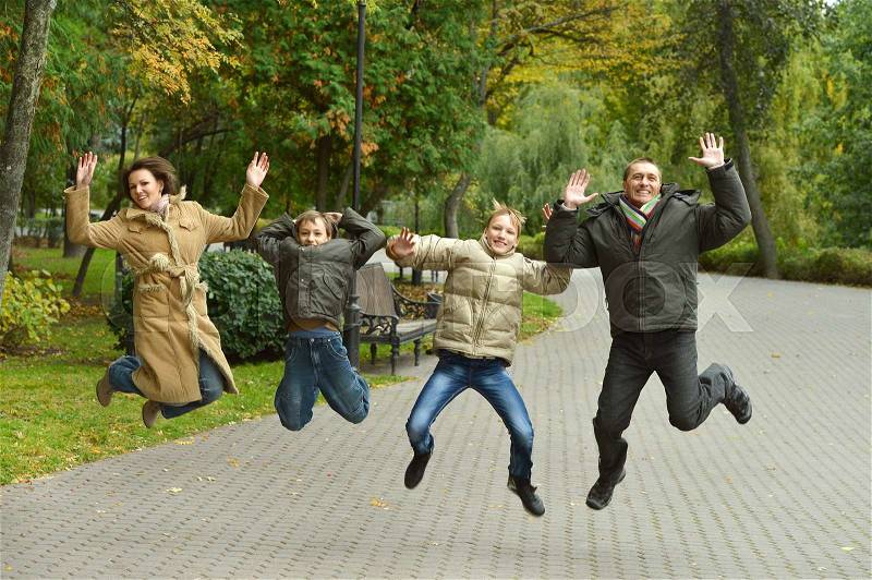 Portrait of a happy family jumping in autumn park, stock photo