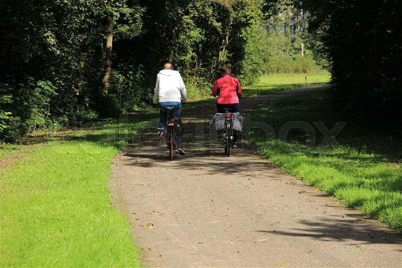 Couple, man and wife, are biking in the park at the summery autumn day at the country side, stock photo