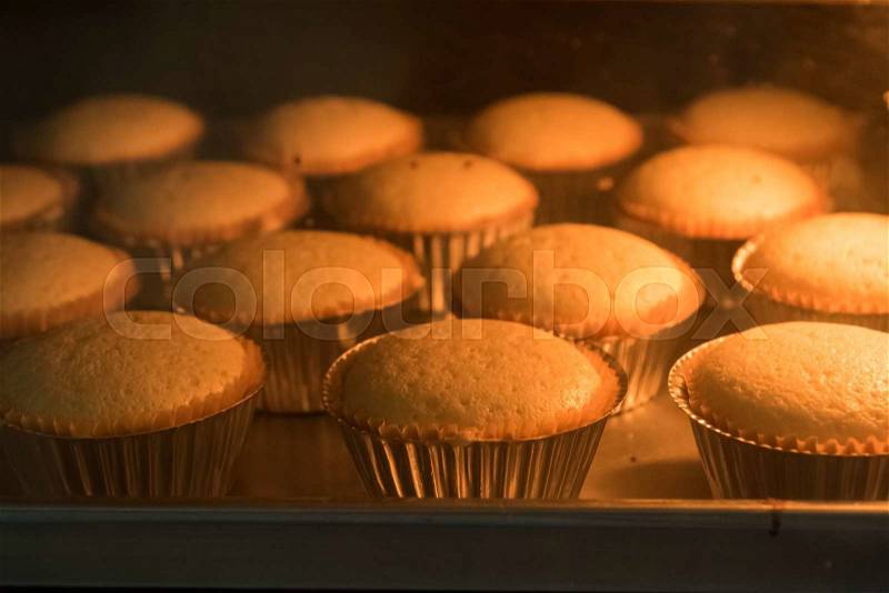 Baked cup cakes on a tray in the oven, stock photo
