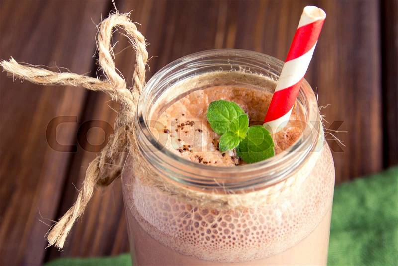 Chocolate smoothie (milkshake) with mint and straw in jar on dark wooden table, stock photo