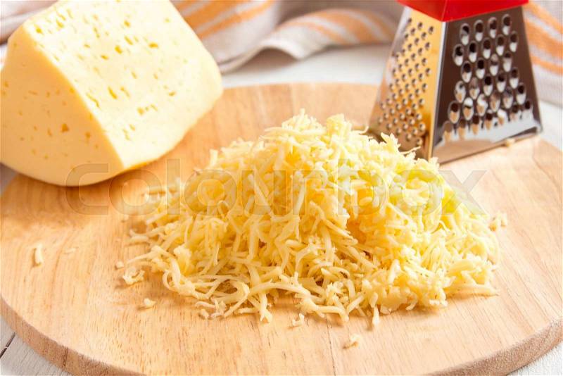 Grated cheese on wooden cutting board, stock photo