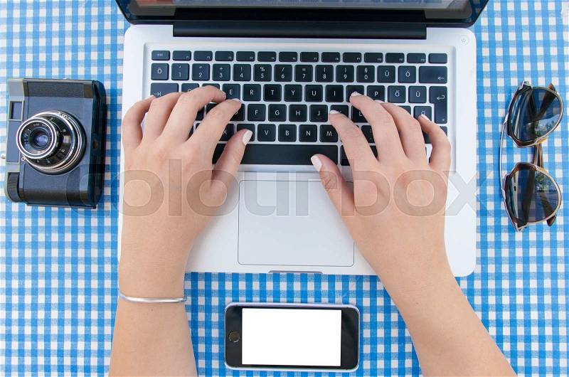 Female hands typing on laptop keyboard from above, stock photo