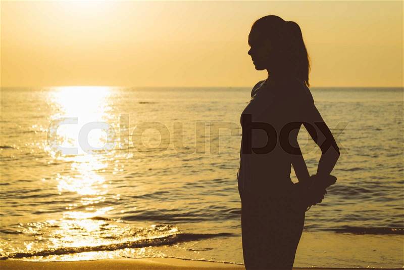 Silhouette of a slender woman on the beach during the morning exercise, stock photo
