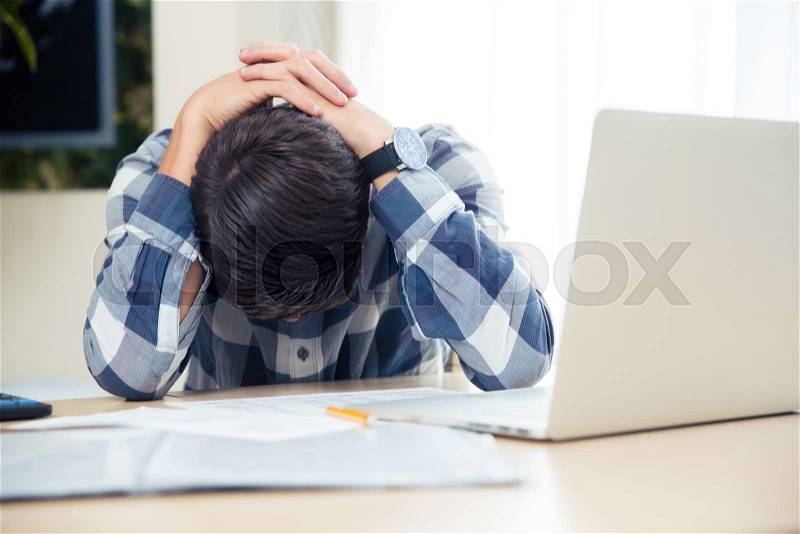 Portrait of a worried man sitting at the table at home, stock photo