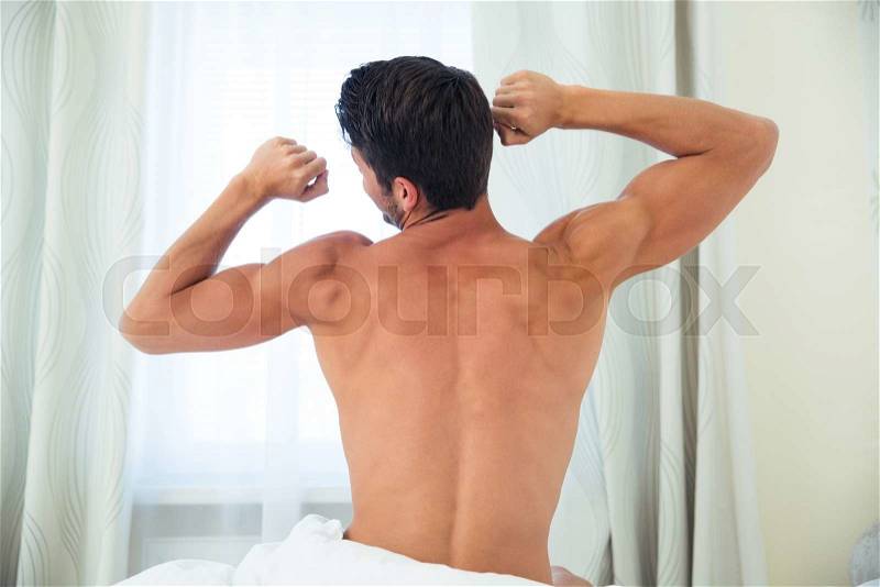 Portrait of a man waking up and stretching hands at home, stock photo