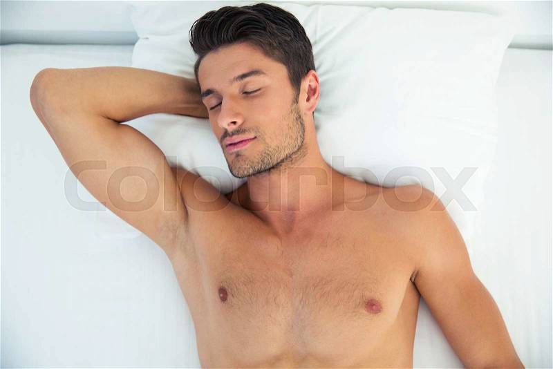 Portrait of a nude man sleeping in the bed at home, stock photo