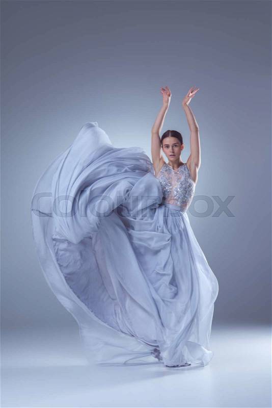 The beautiful ballerina dancing in long lilac dress on lilac background, stock photo