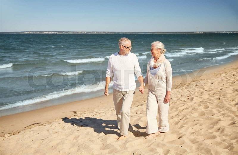 Family, age, travel, tourism and people concept - happy senior couple walking along summer beach, stock photo