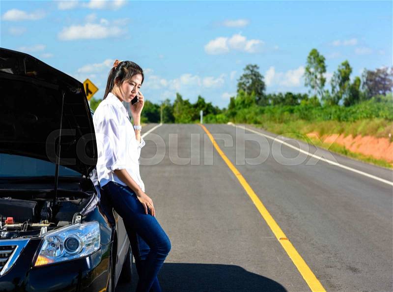 Young girl with broken down car with hood open call for help, stock photo