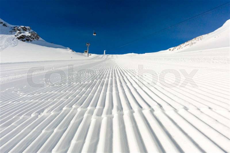 Fresh snow at recently groomed ski run at ski resort in the Alps on a sunny winter day, stock photo