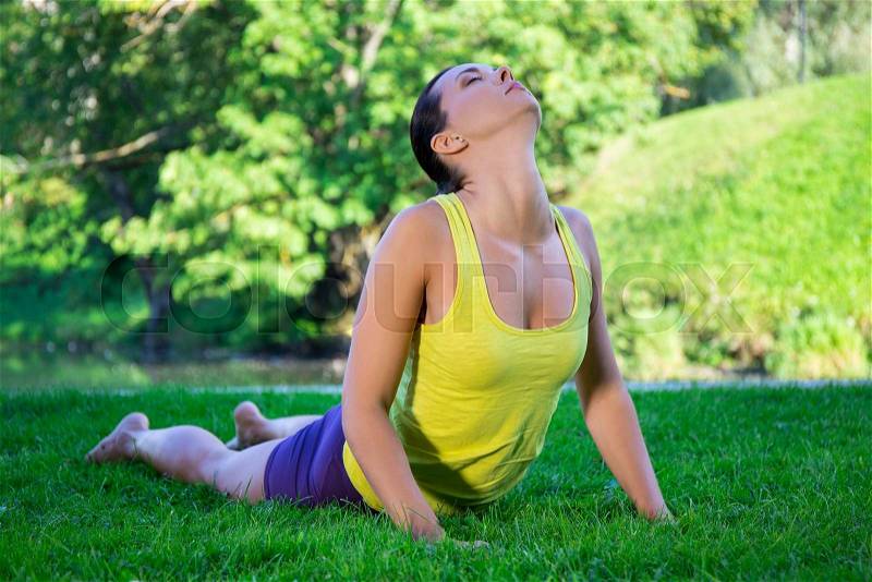 Young woman doing yoga exercises in summer park - cobra pose, stock photo