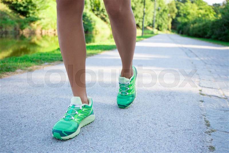 Runner woman feet running on road in summer park, stock photo
