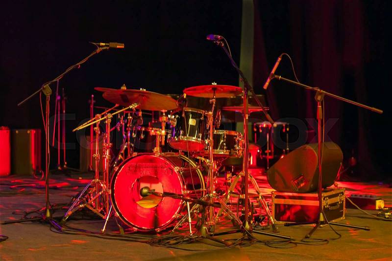 Drums set on stage lit by red light, stock photo
