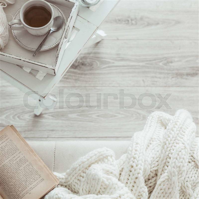 Still life details, cup of tea on retro vintage wooden tray on a coffee table in living room, top view point. Lazy winter weekend with a book on the sofa, stock photo
